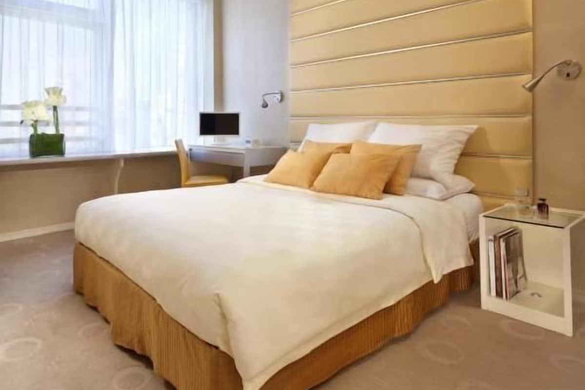 A hotel room with a bed, a desk, and a window with curtains.