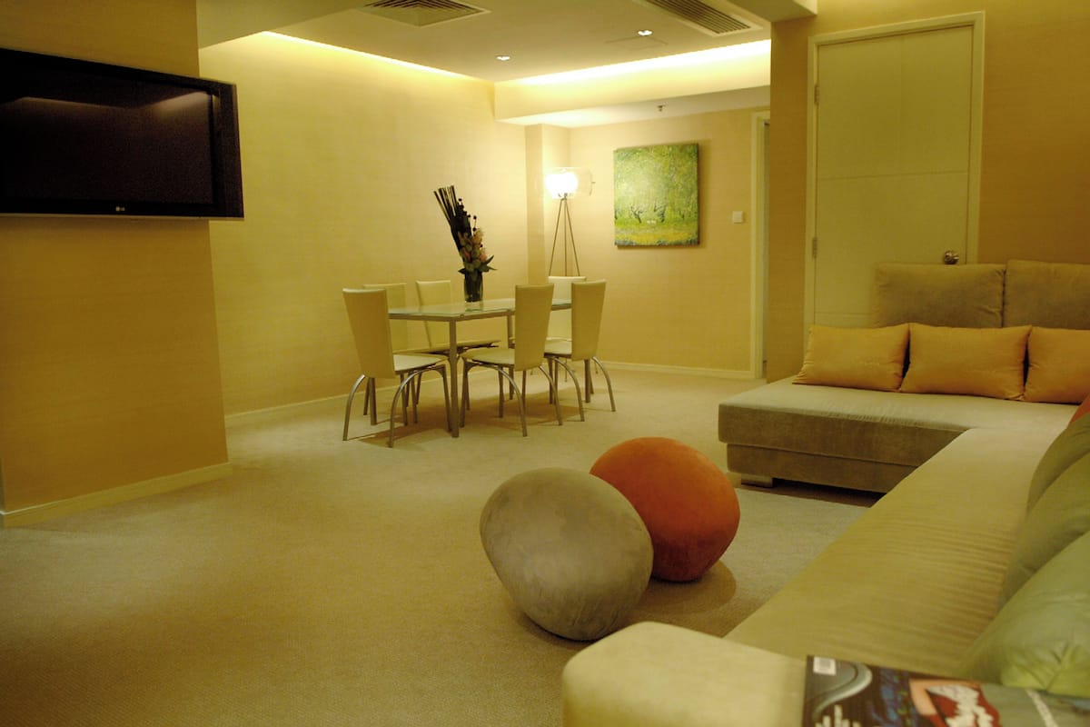 A modern living room with a sofa, ottoman, and a dining table with chairs.