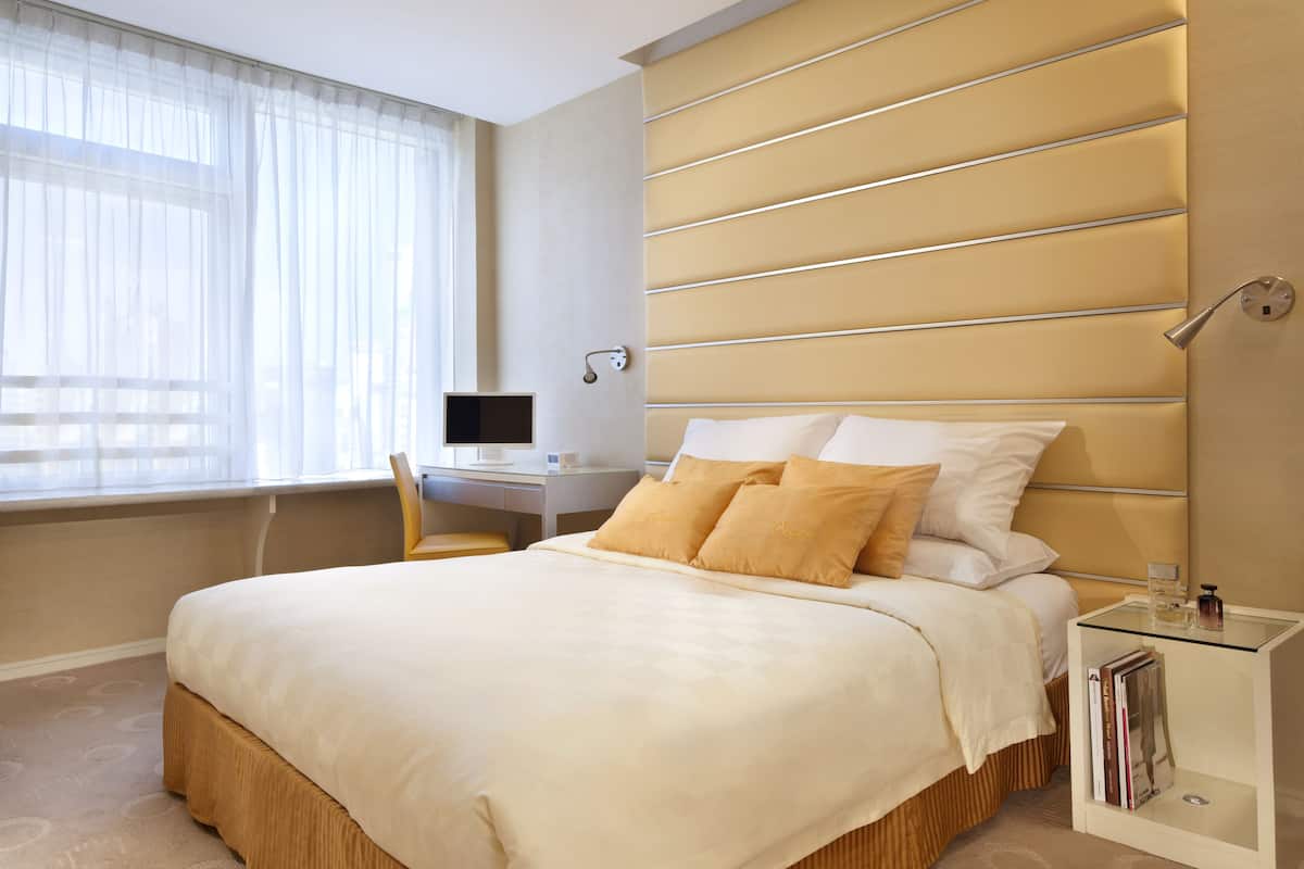 A modern hotel room with a large bed, a desk, and a nightstand.