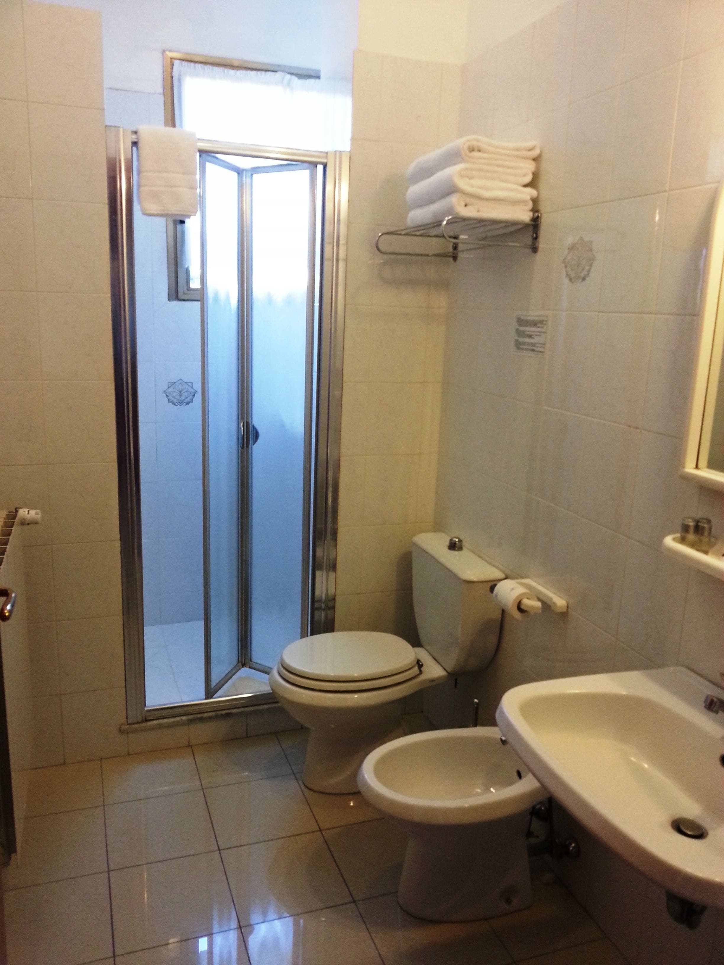 Un baño con ducha envuelta en vidrio, inodoro y lavamanos.