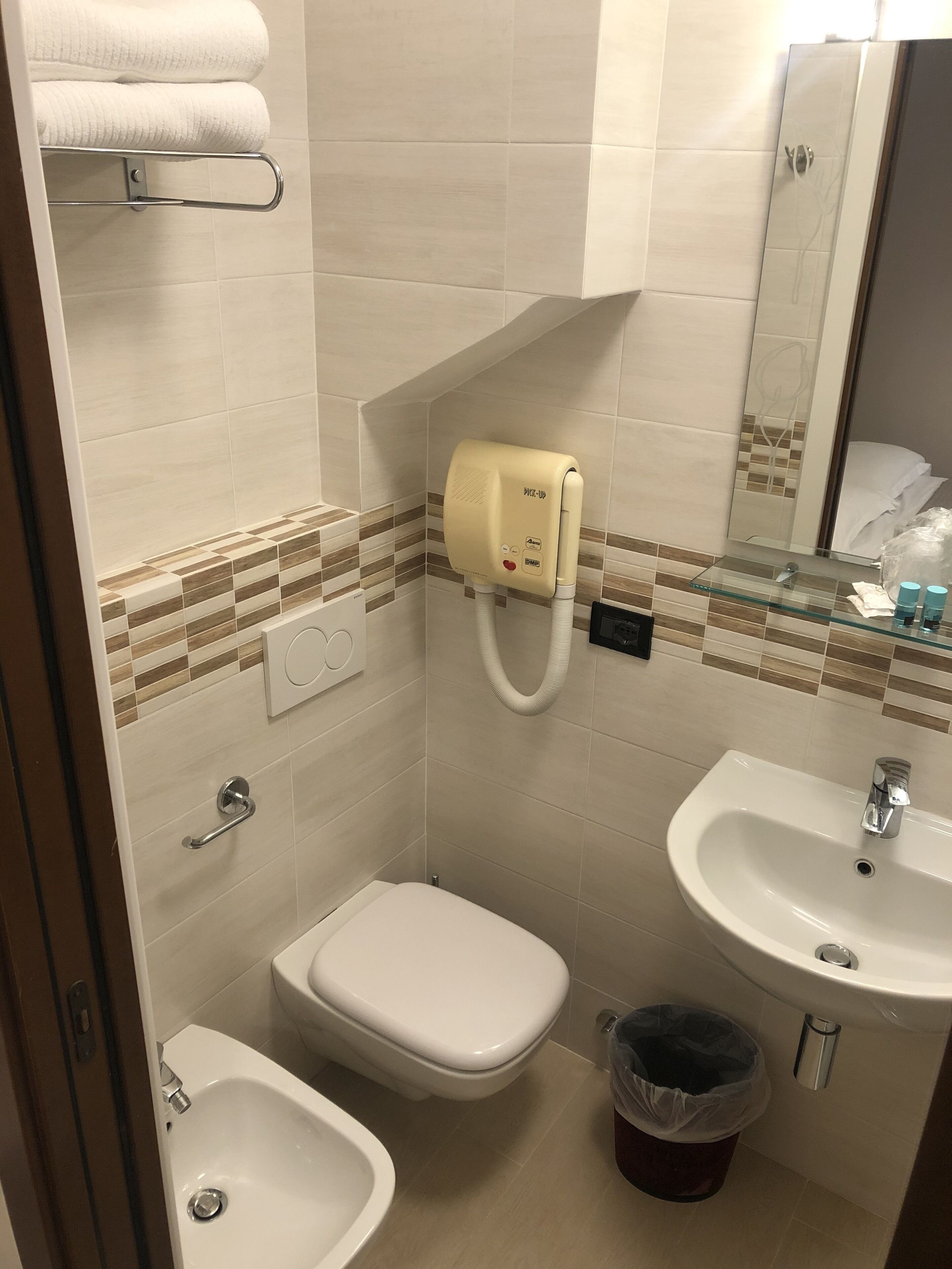 A bathroom with a toilet, bidet, sink, and towel rack.