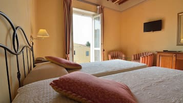 Une chambre d’hôtel avec deux lits, une télévision, une lampe et une vue sur l’extérieur.