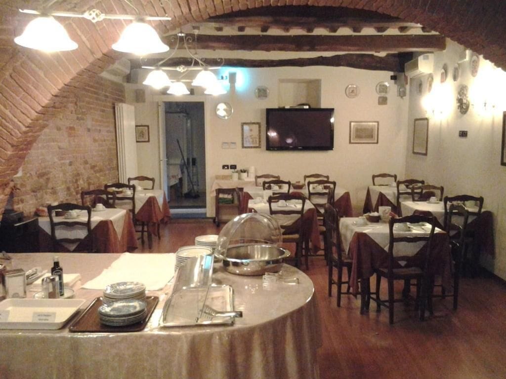 A dining area with multiple tables, chairs, a buffet setup, and a television on the wall.