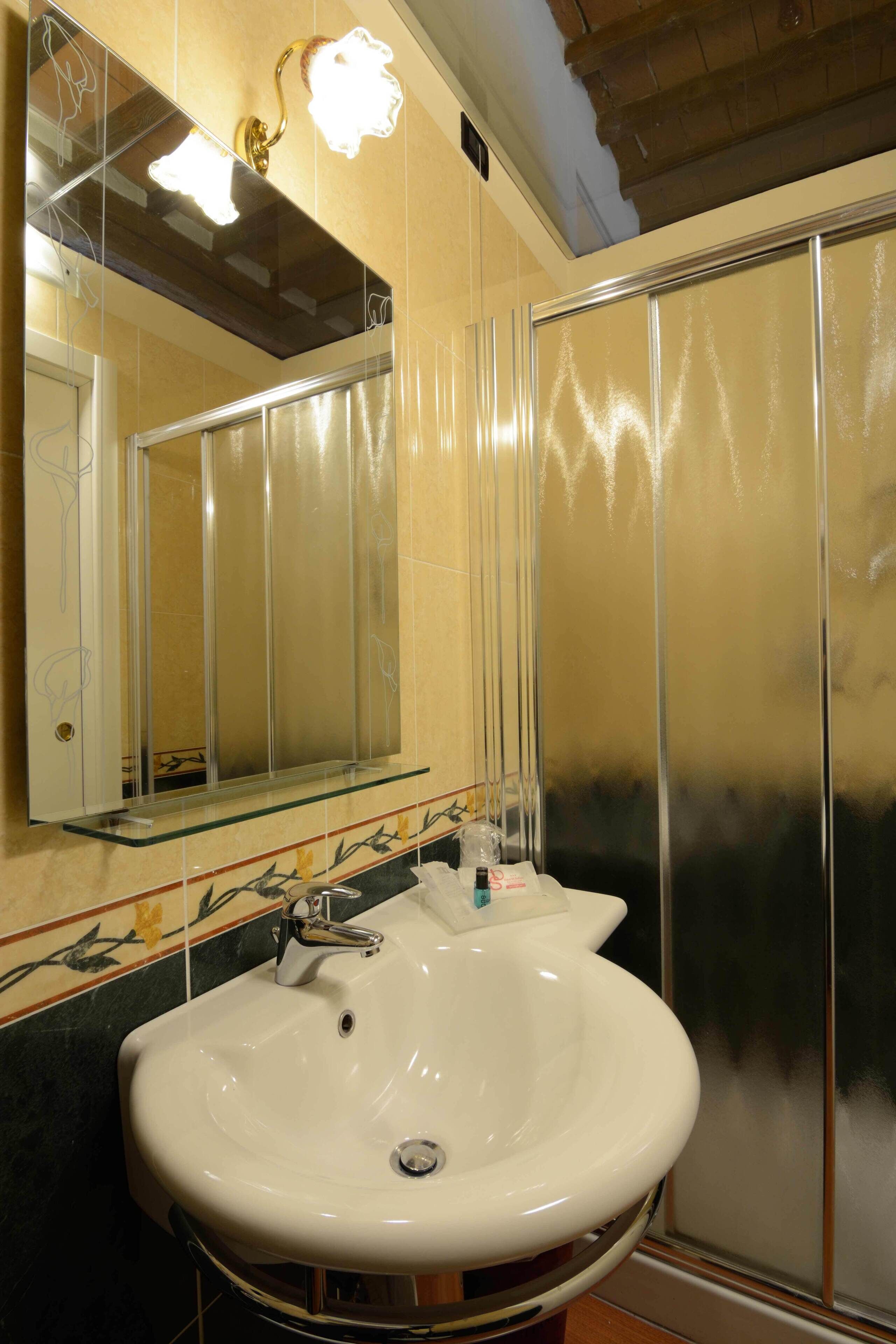 Ein Badezimmer mit einem weißen Waschbecken, einem Spiegel und einer Duschkabine.