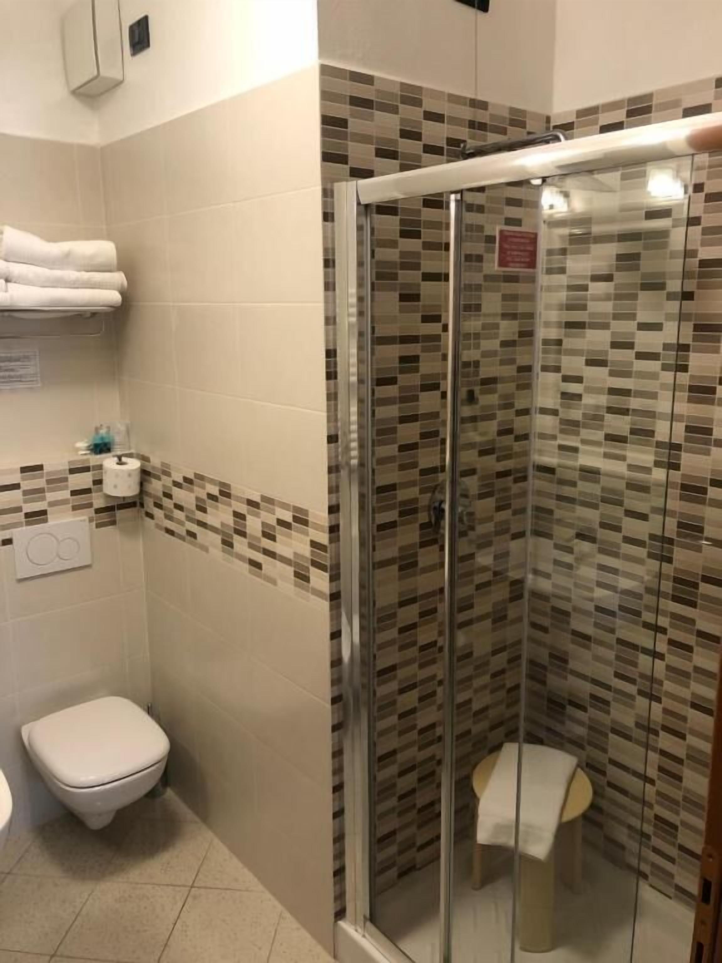A shower area with a glass door, a toilet, and a towel rack.