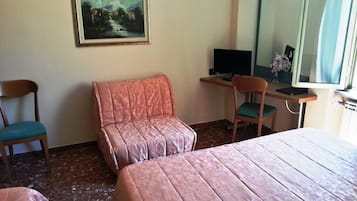 Habitación de hotel con dos camas, un escritorio con computadora, una silla y un cuadro en la pared.