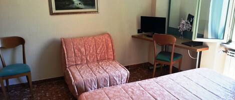 A hotel room with two beds, a desk with a computer, a chair, and a painting on the wall.