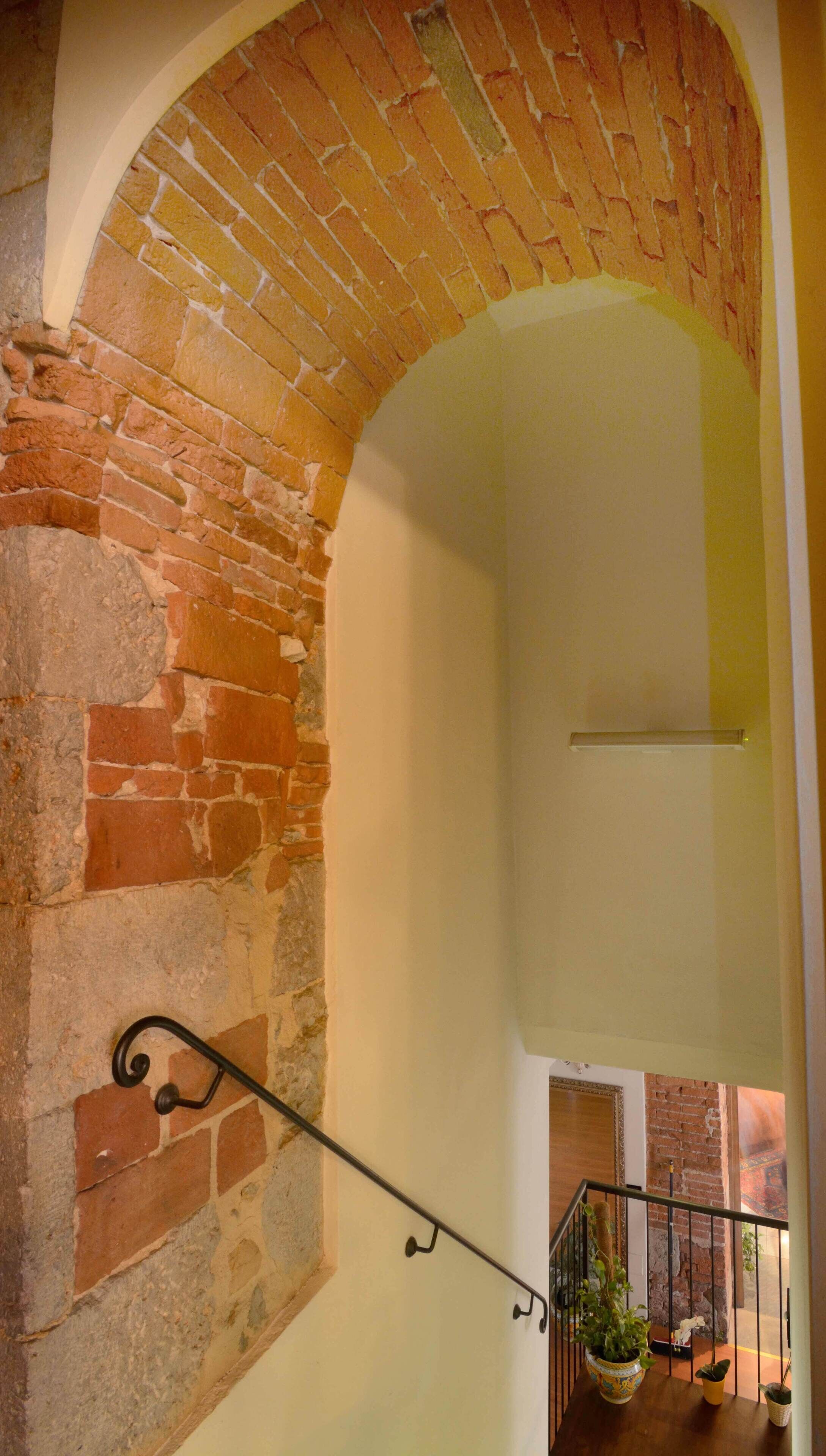 A staircase with a brick archway leading to a lower level.