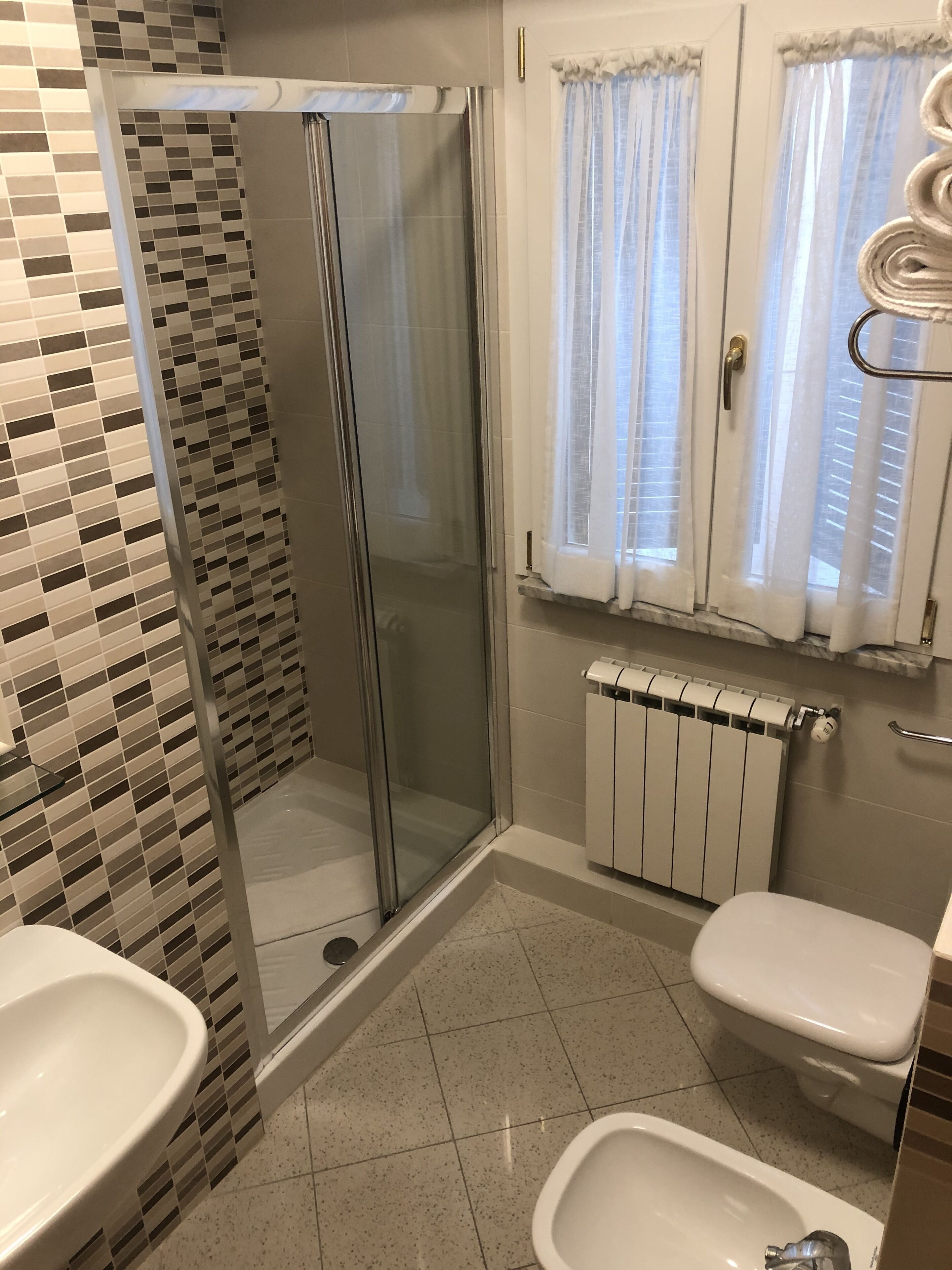 Een badkamer met een douche, toilet, bidet en een betegelde vloer.