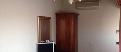 A room with a wooden cabinet, a television on a stand, and a chandelier.