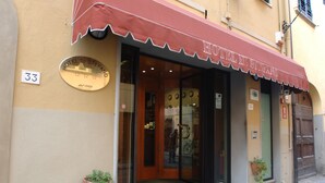 Exterior do Hotel Di Stefano, com fachada clássica, porta numerada e toldo vermelho.