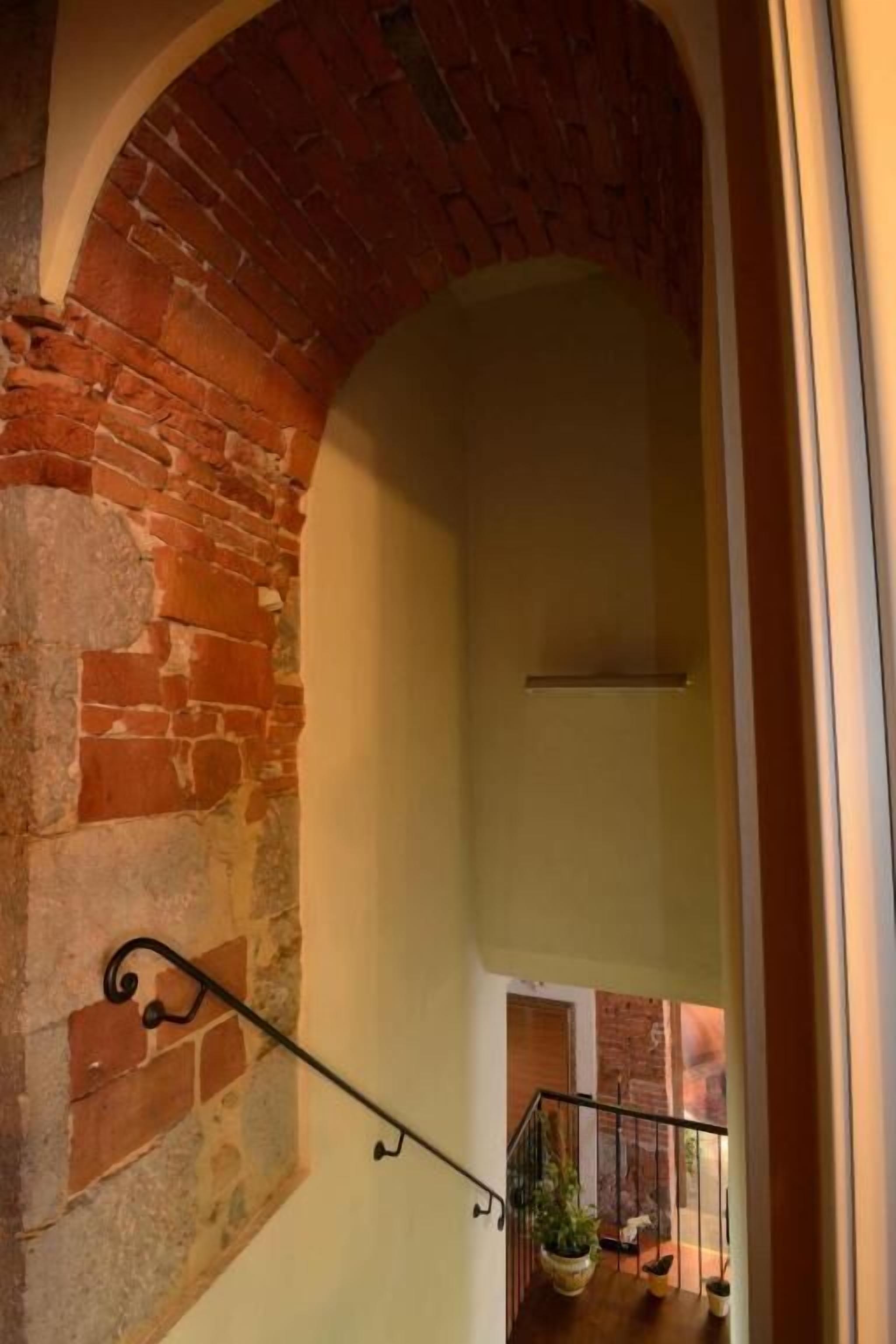 Uma escadaria com uma parede de tijolos de um lado e uma parede lisa do outro, descendo para um nível inferior.
