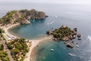 An aerial view of a coastal area with a beach, boats, and rocky terrain. - Grand Hotel San Pietro Taormina - Preferred Hotels & Resorts (Taormina)