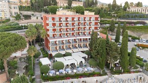 Un hotel de varios pisos con balcones, mobiliario exterior y un jardín ajardinado.