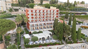 A multi-story hotel with balconies, outdoor seating, and a landscaped garden.