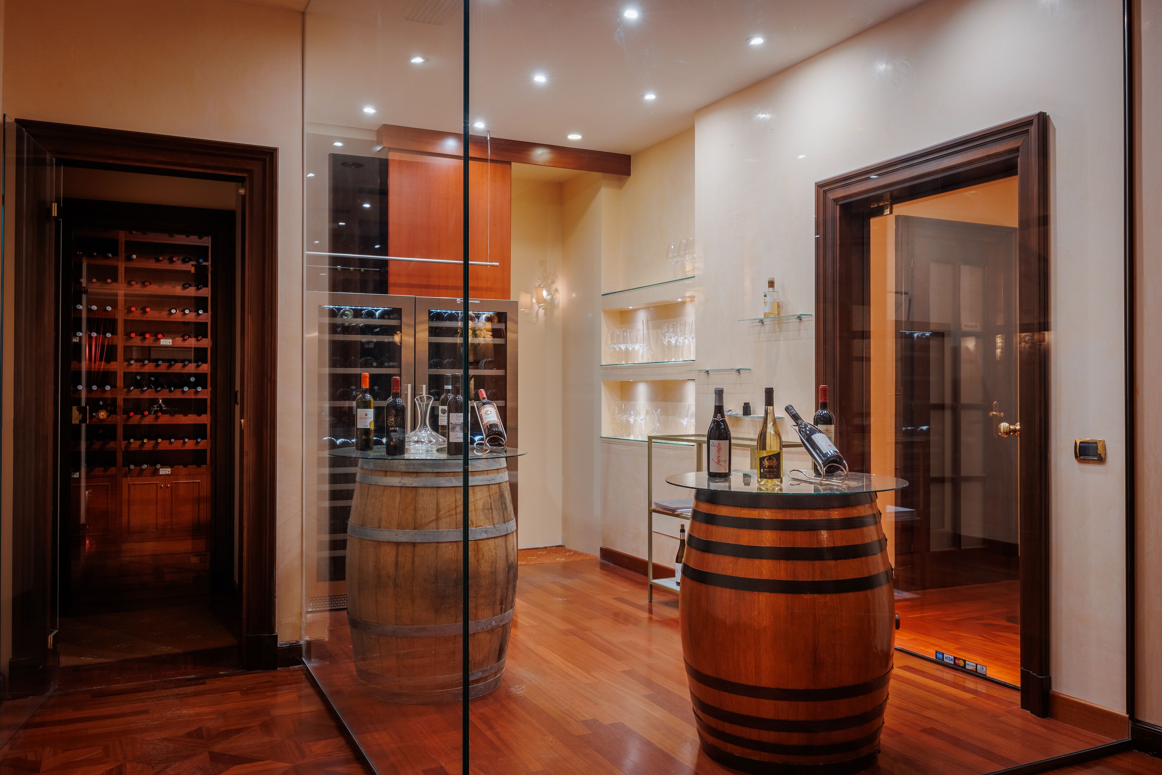 Un interior moderno con pisos de madera, una cava de vinos y una zona de bar con barriles.