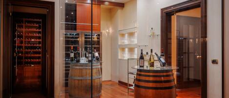 Un interior moderno con pisos de madera, una cava de vinos y una zona de bar con barriles.