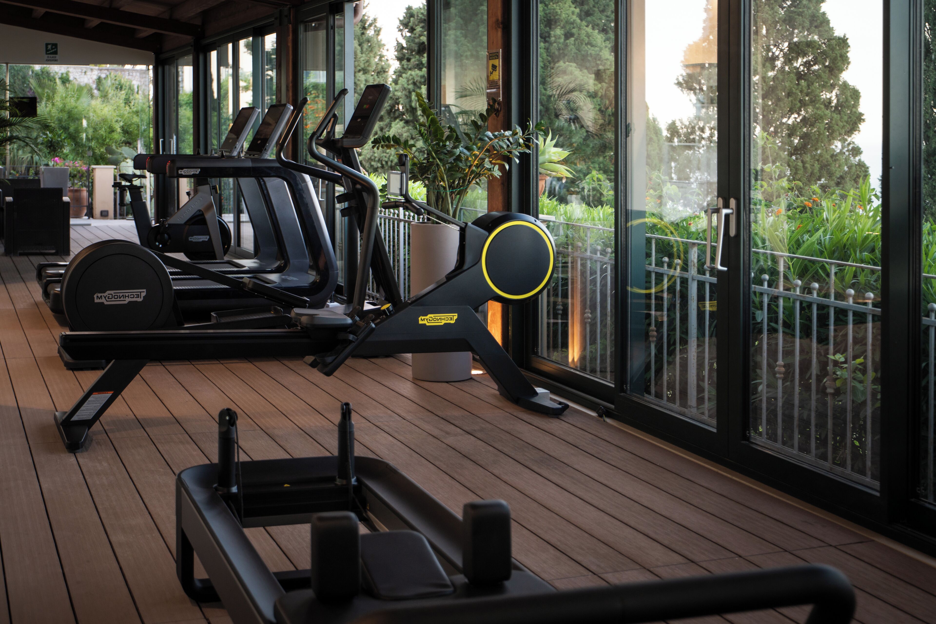 A gym with exercise equipment, large windows, and a wooden deck.