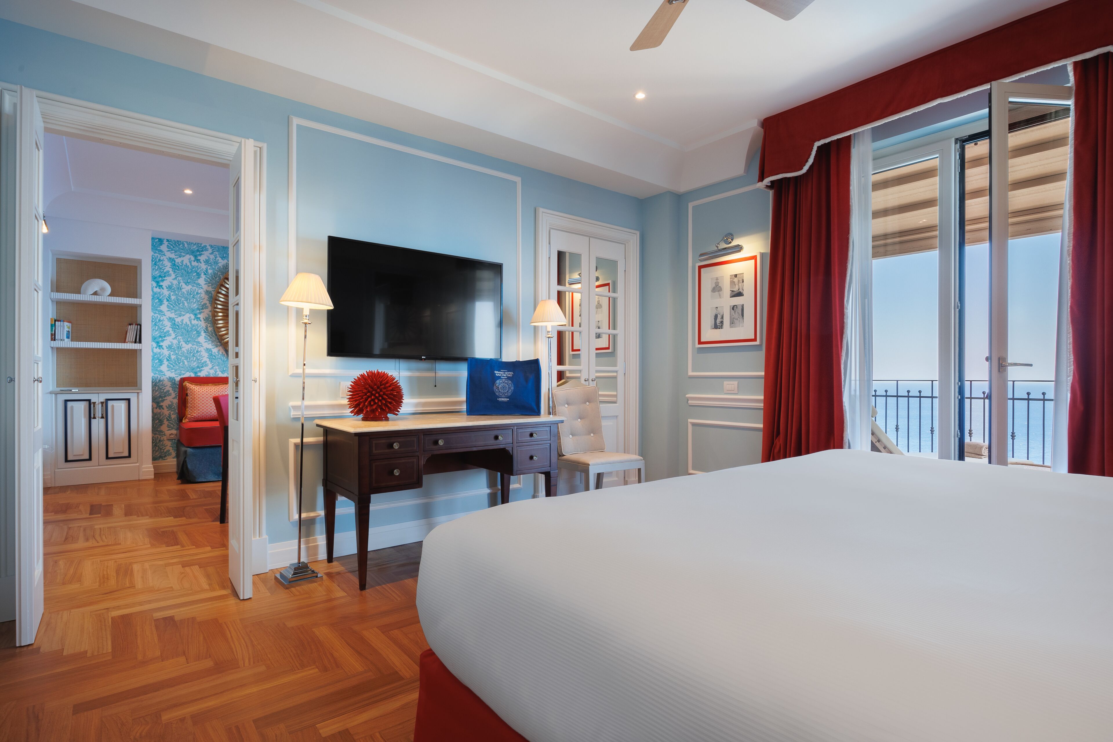 Quarto de hotel com uma cama grande, uma escrivaninha com TV de tela plana, uma cadeira e vista para o exterior.