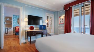 Quarto de hotel com uma cama grande, uma escrivaninha com TV de tela plana, uma cadeira e vista para o exterior.