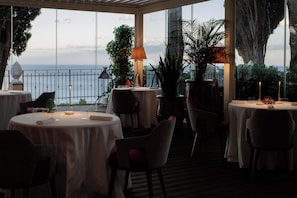 A restaurant with round tables, chairs, and potted plants. - Grand Hotel San Pietro Taormina - Preferred Hotels & Resorts (Taormina)