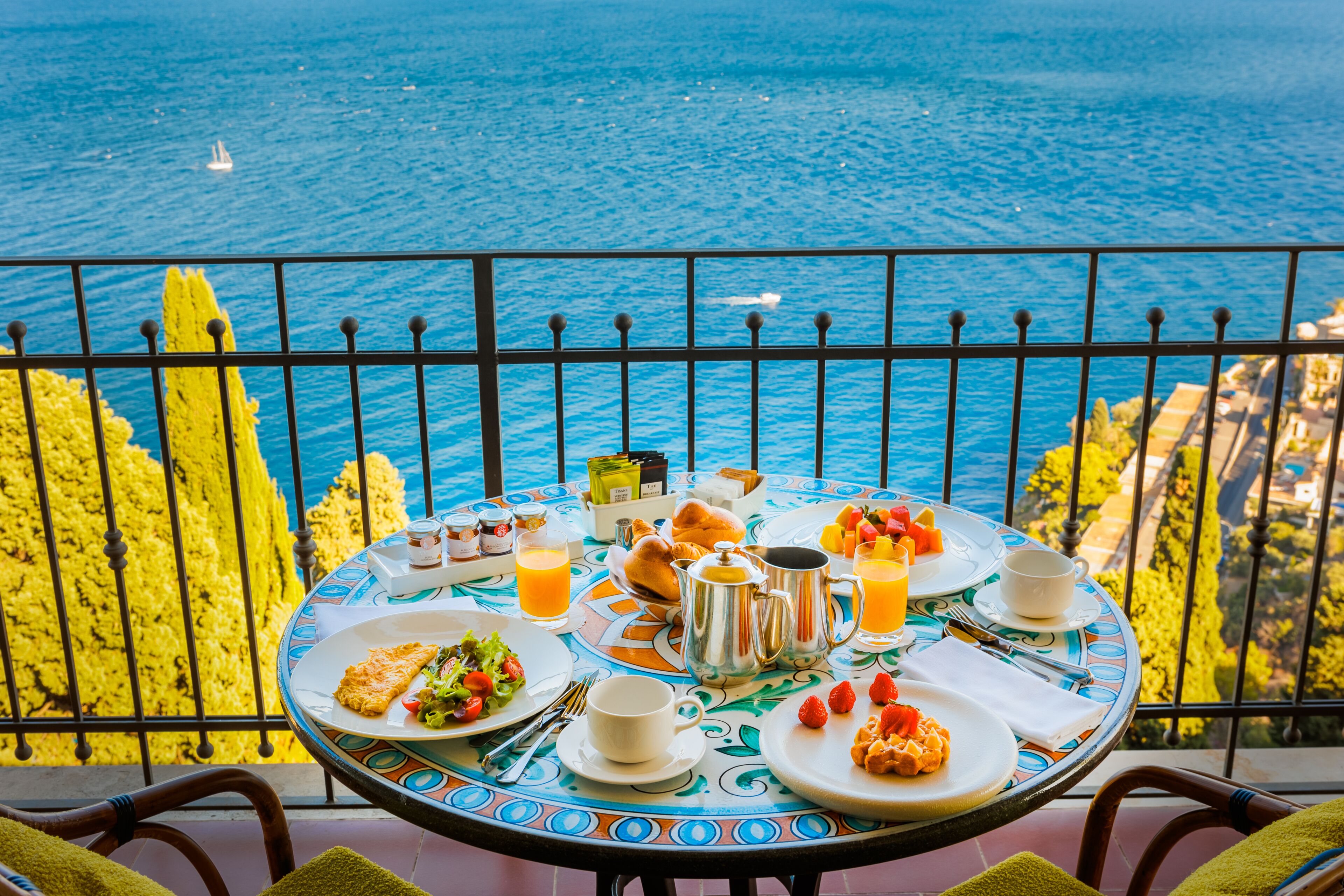A table set with breakfast items and a view of the sea.
