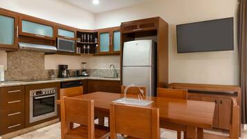 A modern kitchen with granite countertops, stainless steel appliances, wooden cabinets, and a dining area with a table and chairs.