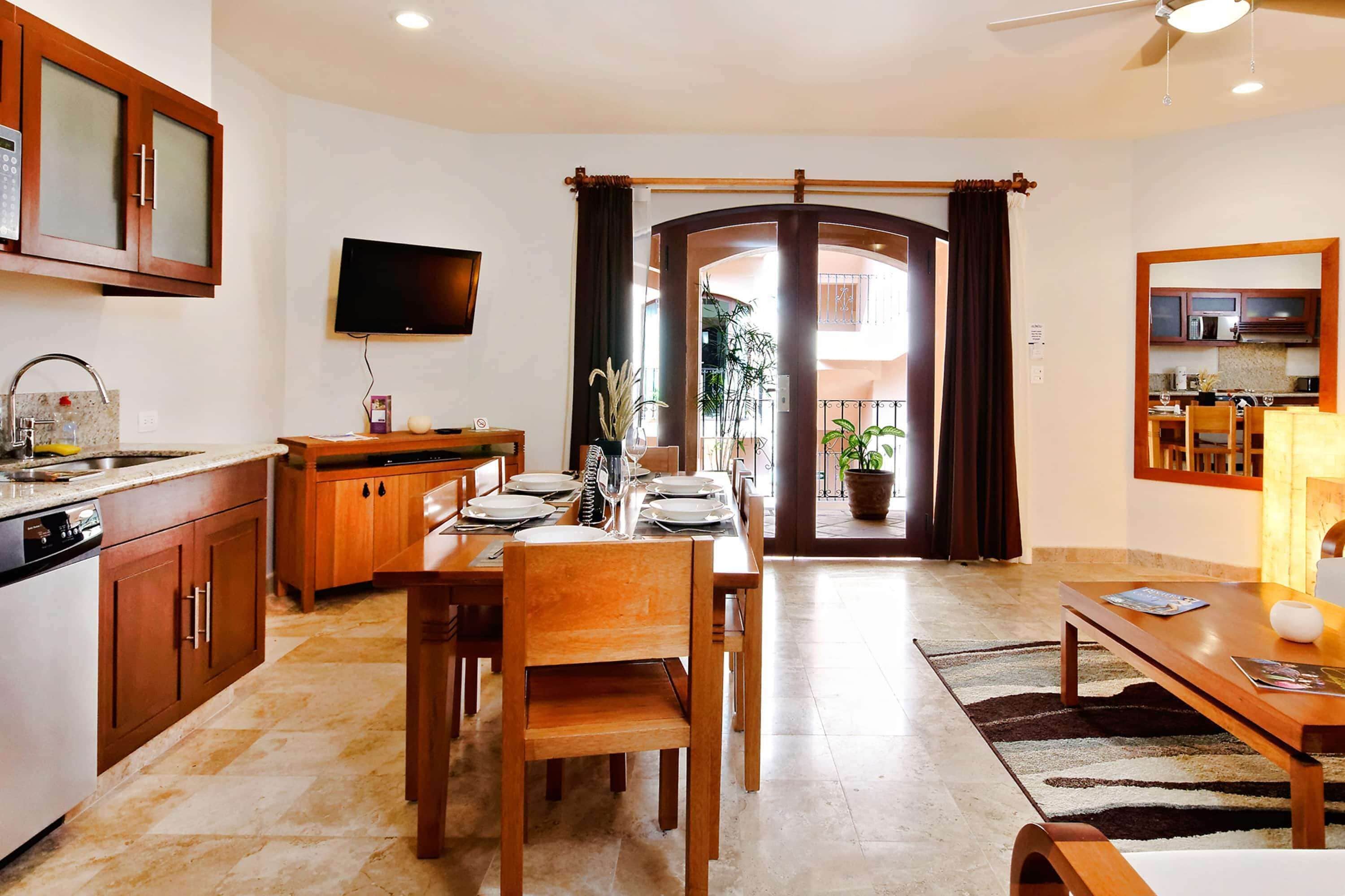 A modern kitchen with wooden cabinets, a built-in oven, and a flat-screen TV.