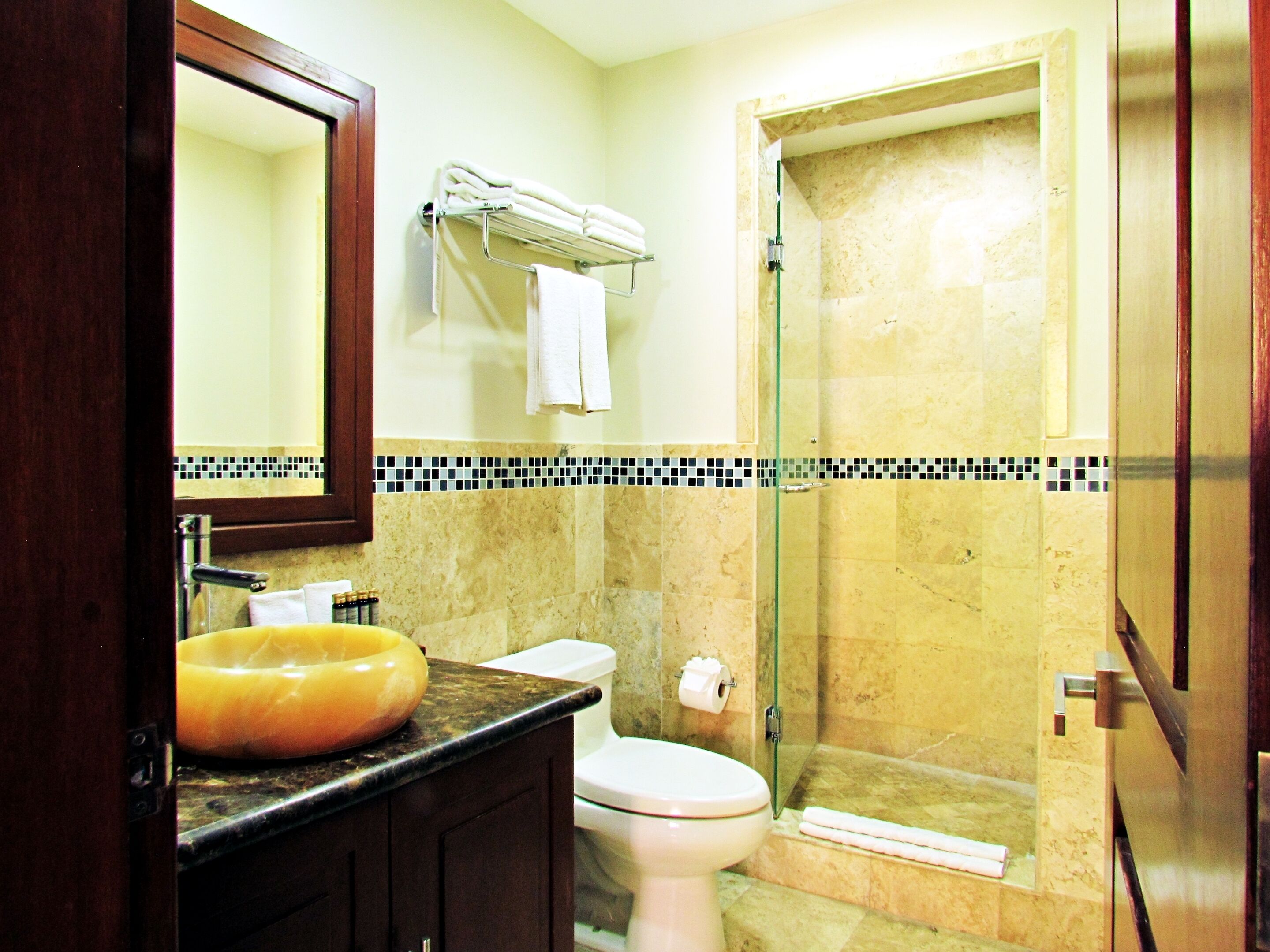 Une salle de bain avec un lavabo en marbre, des toilettes, une douche à parois de verre et un porte-serviettes.