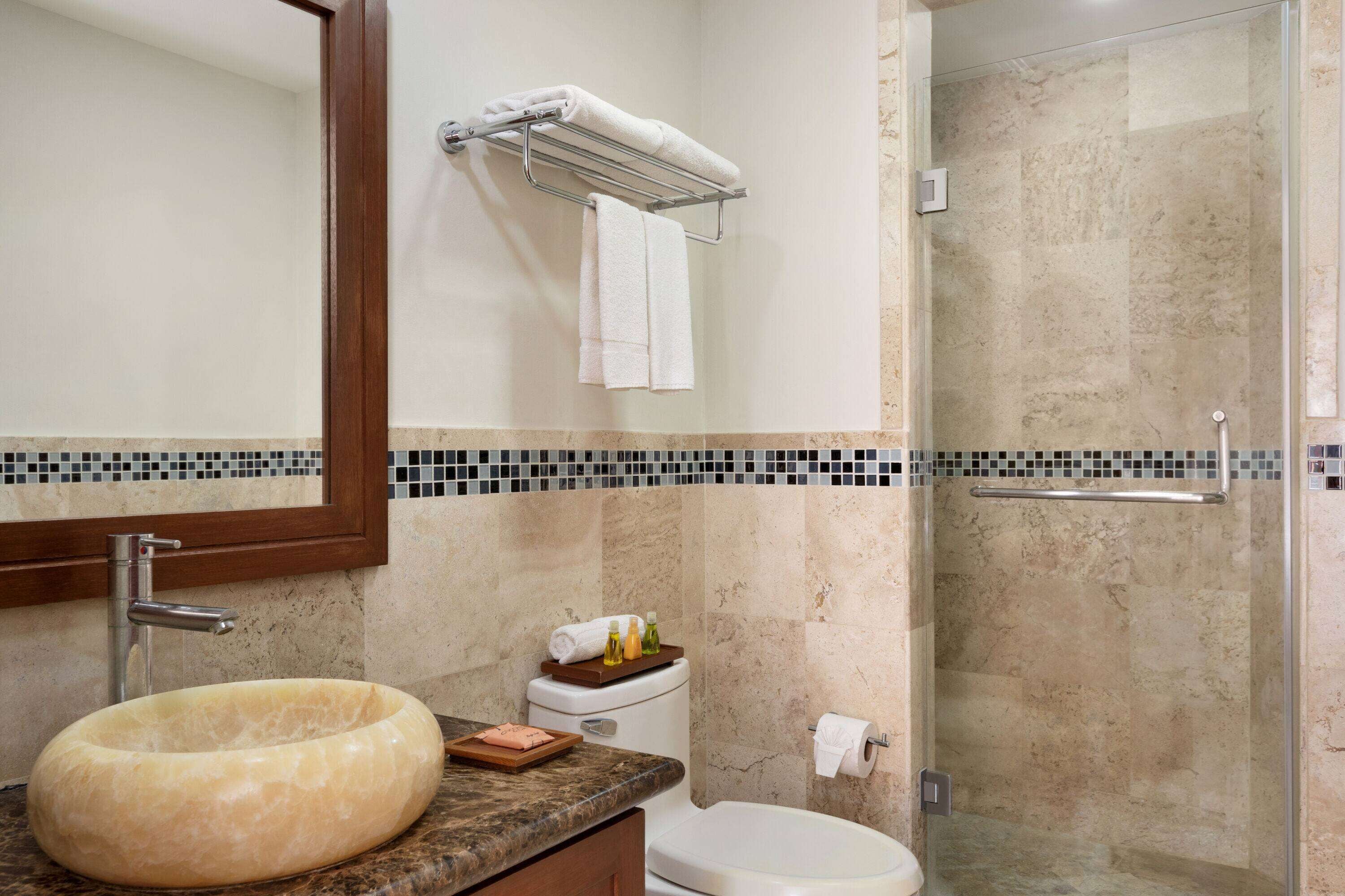 Un bagno con lavabo in marmo, un water, una doccia e uno specchio.