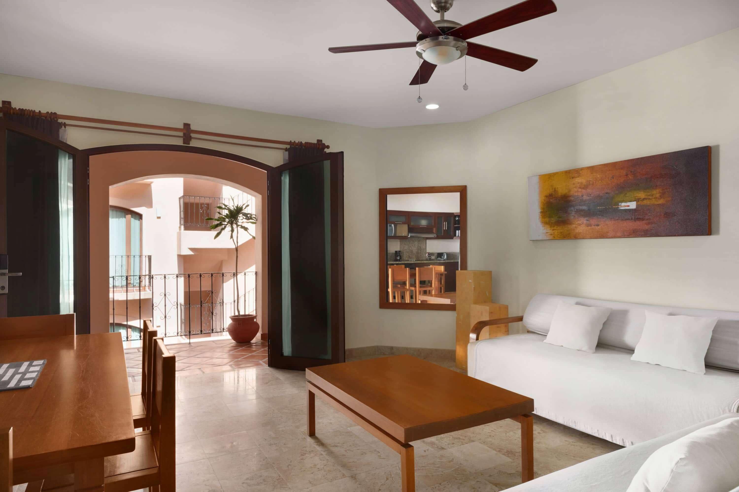 A modern living room with a wooden coffee table, a white sofa, and a ceiling fan.