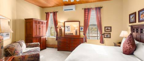 Een slaapkamer met een bed, houten plafond, een dressoir, een spiegel en een raam met gordijnen.