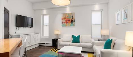 A modern living room with a white sofa, a coffee table, and a TV mounted on the wall.