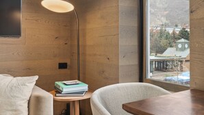 Une pièce moderne avec des murs en bois, une grande fenêtre, un bureau, une chaise, une lampe et une bibliothèque.