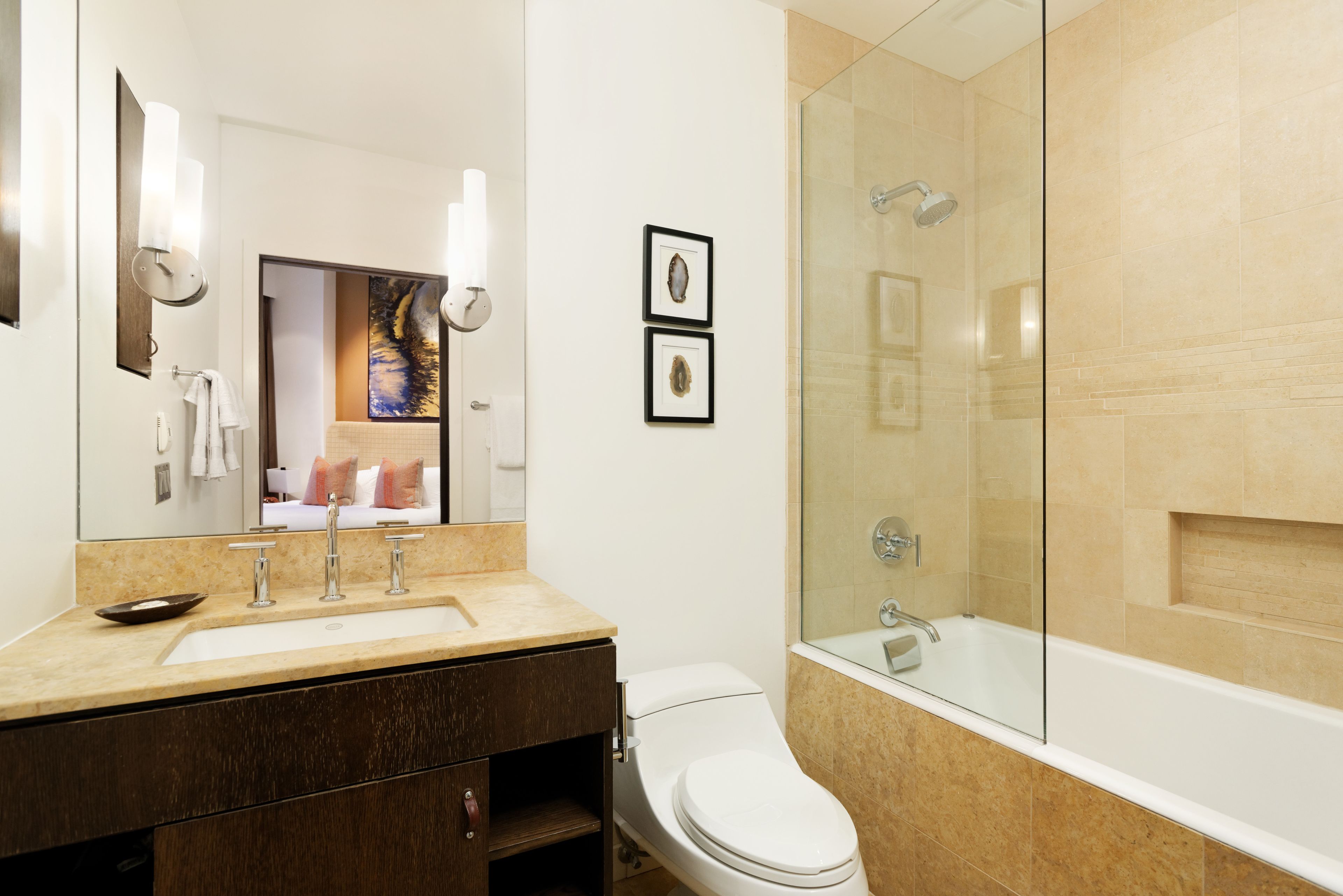 Une salle de bain moderne équipée d’un lavabo, d’un miroir, de toilettes et d’une douche à parois de verre.