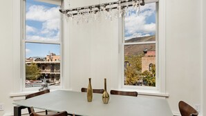 Un coin repas comprenant une table et des chaises, deux vases décoratifs et un lustre.