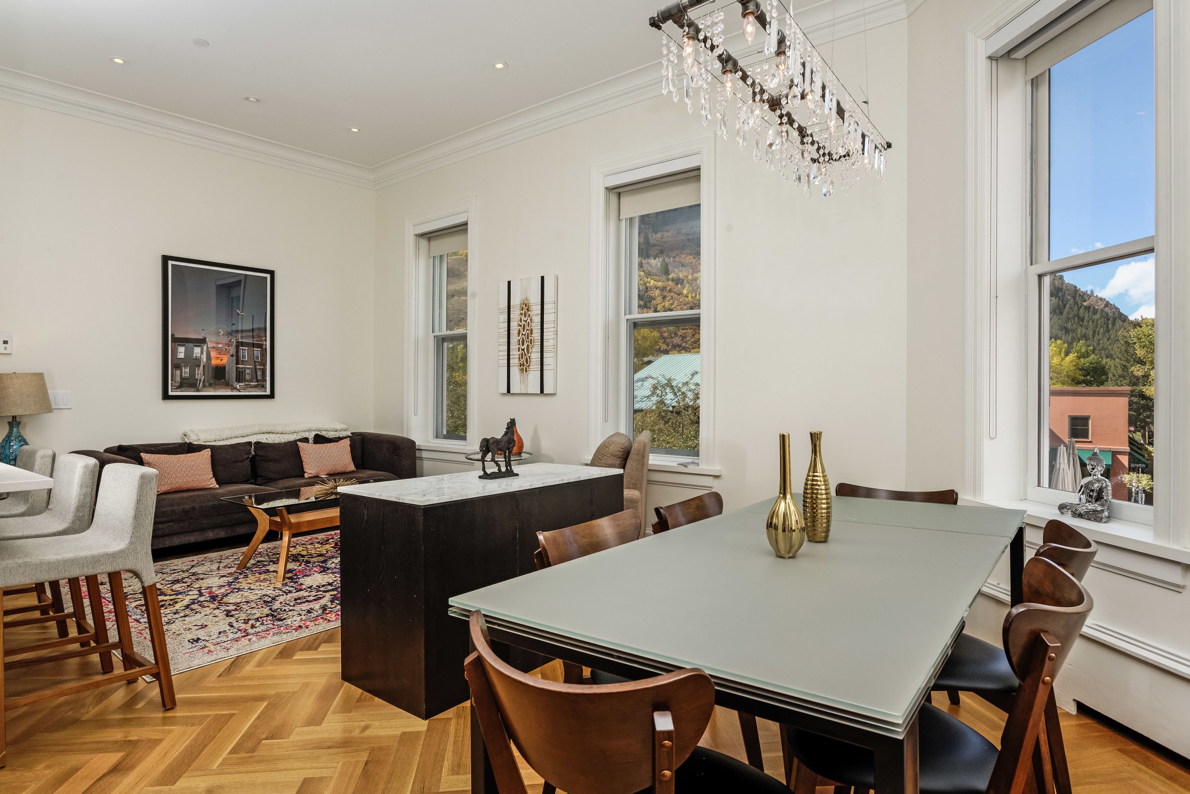 A spacious living room with a large dining table, a sofa, and a chandelier.