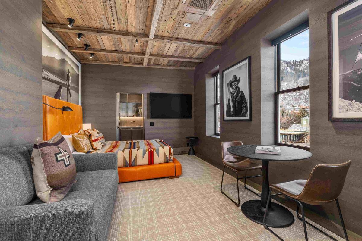A modern living room with a sofa, a coffee table, and a TV. There is a window with a view of a snowy landscape.