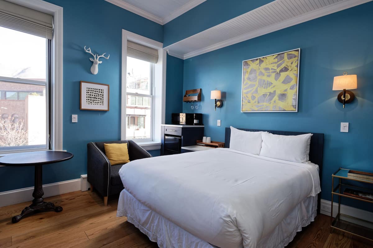 A bedroom with a large bed, a desk, a chair, and a window.
