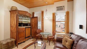 A cozy living room with a wooden cabinet, leather sofa, and a glass table.