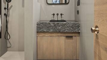 Un baño moderno con ducha, lavamanos con espejo y puerta de madera.