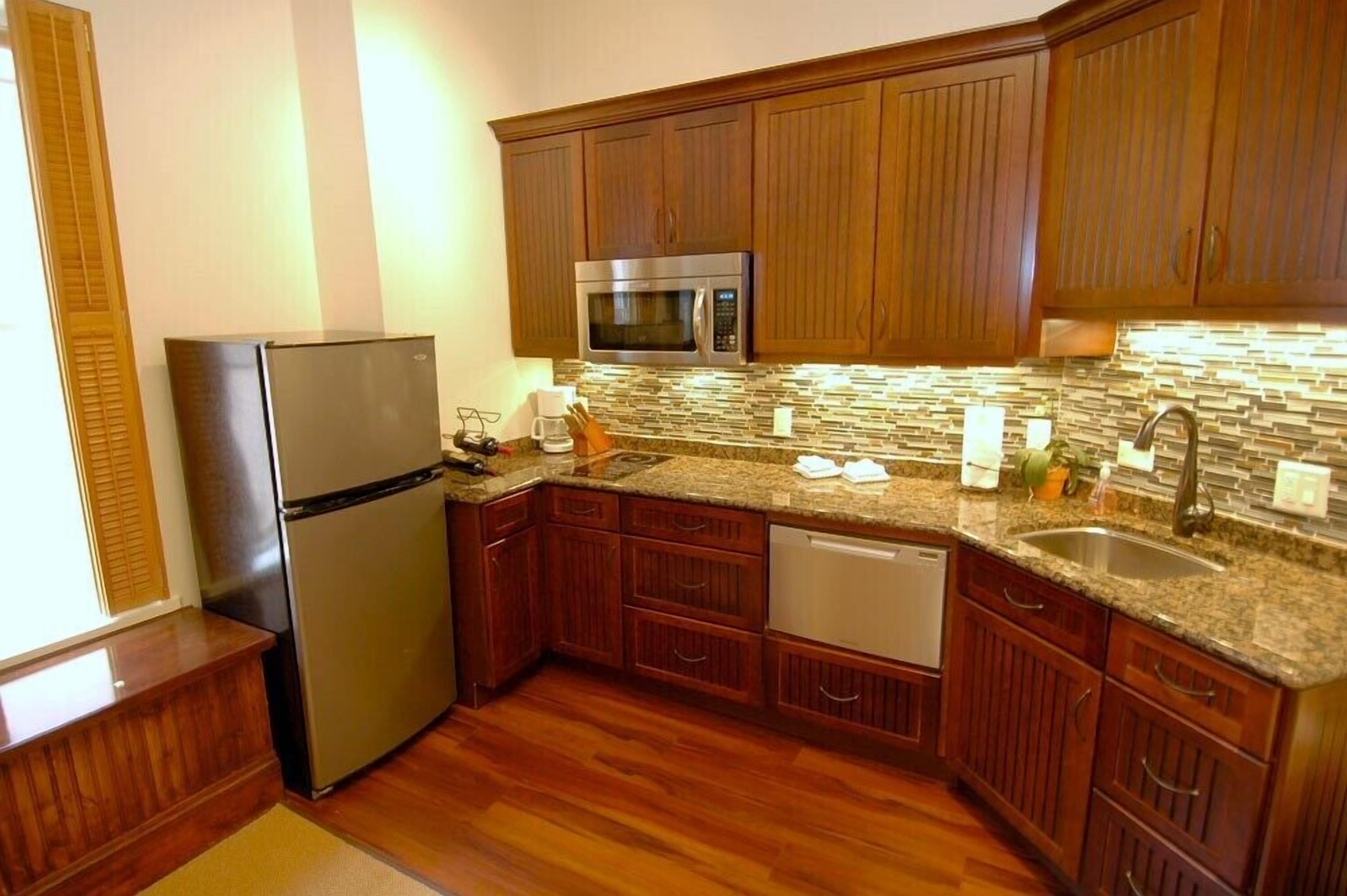 A kitchen with wooden cabinets, a stainless steel refrigerator, a microwave, and a dishwasher.
