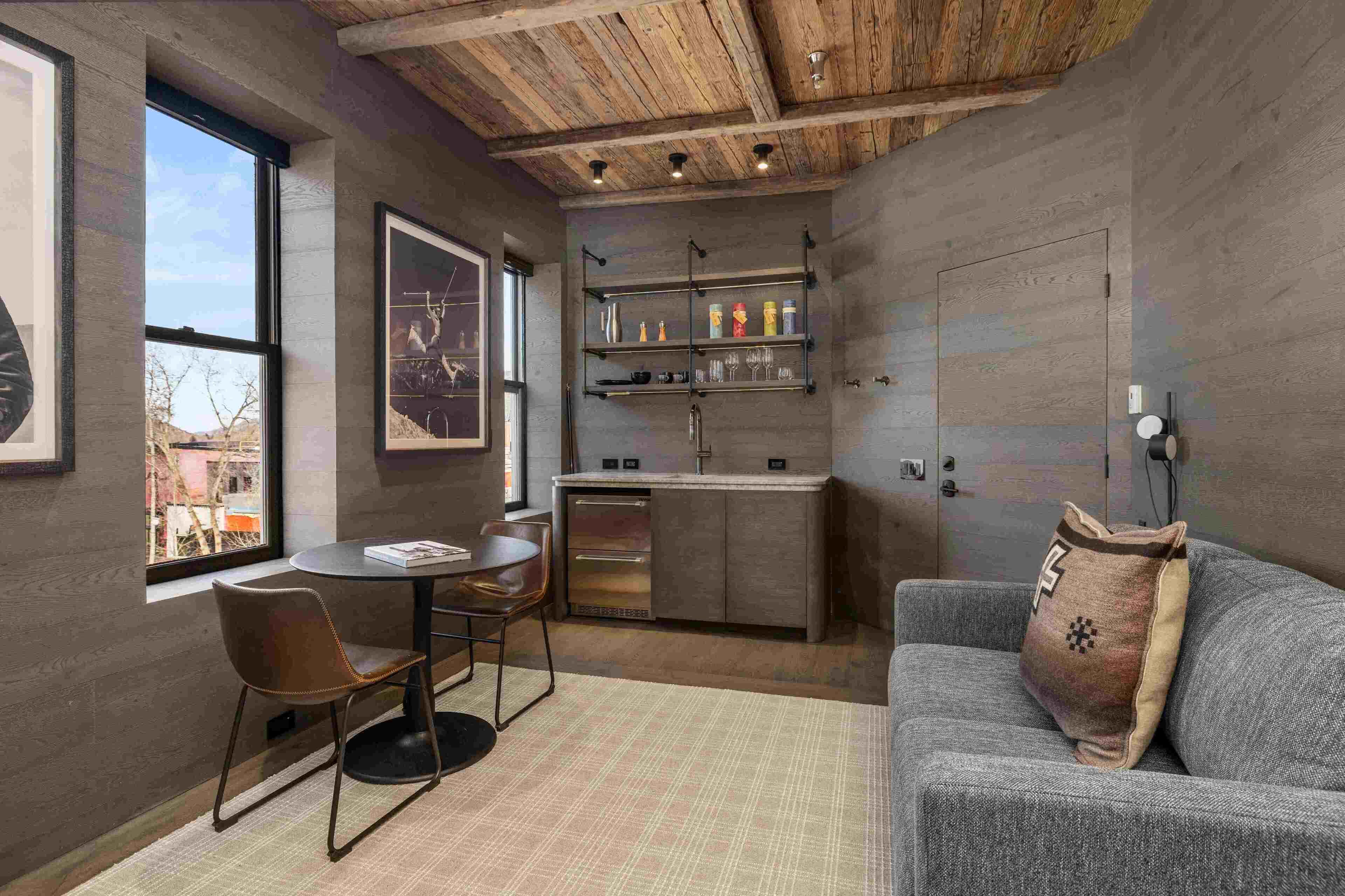 A compact living space with a kitchenette, a dining area with a table and chairs, and a sofa with a decorative pillow.