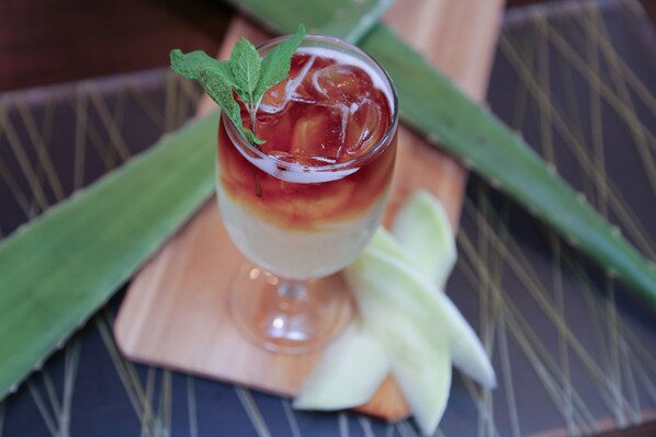 A cocktail glass with a mint garnish on a wooden coaster, accompanied by a slice of lime. - Pilgrim House (Provincetown)