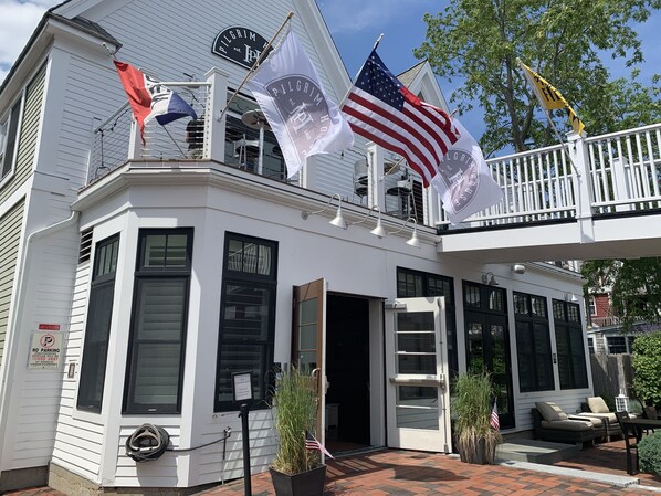 A white building with multiple flags, including the American flag, and a sign indicating VIP parking. - Pilgrim House (Provincetown)