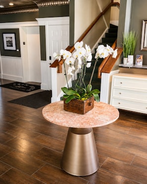 A round table with a wooden planter in the center, a staircase in the background, and a white dresser to the right. - Pilgrim House (Provincetown)
