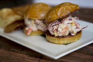 A sandwich with a sesame seed bun and a creamy filling, served on a white plate. - Pilgrim House (Provincetown)