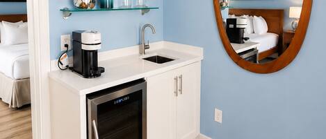 A modern kitchen with a built-in dishwasher, a coffee maker, and glass shelves above the sink.