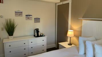 Una habitación de hotel con cama, cómoda, lámpara y cafetera.