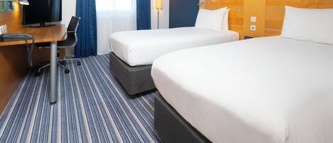 A hotel room with two beds, a desk with a computer, a TV, and a lamp.